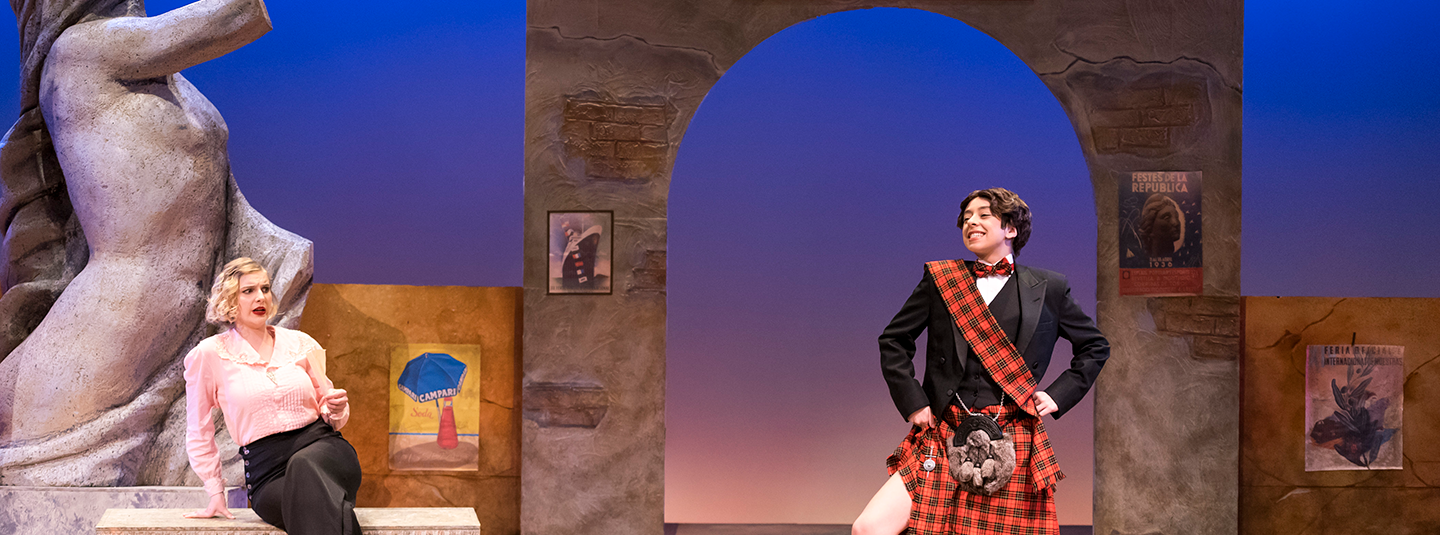 stage production of "Twelfth Night" showing man in Scottish kilt speaking to woman seated on a bench in pink blouse and black pants