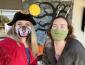 Woman wearing pirate hat and mask on left and another woman wearing a facemask on the right