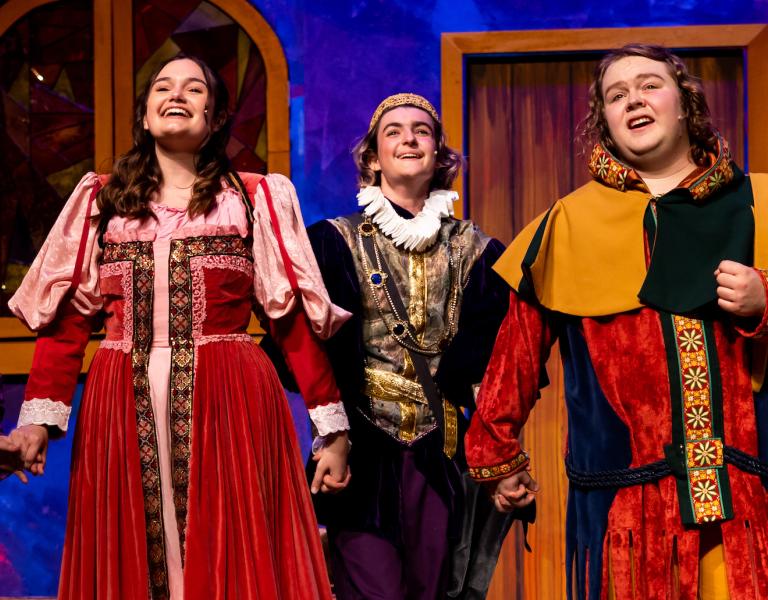 Students in costume holding hands and singing