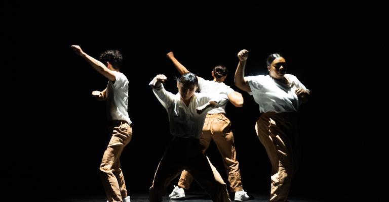 Dancers in a circle with white shirts and khaki pants