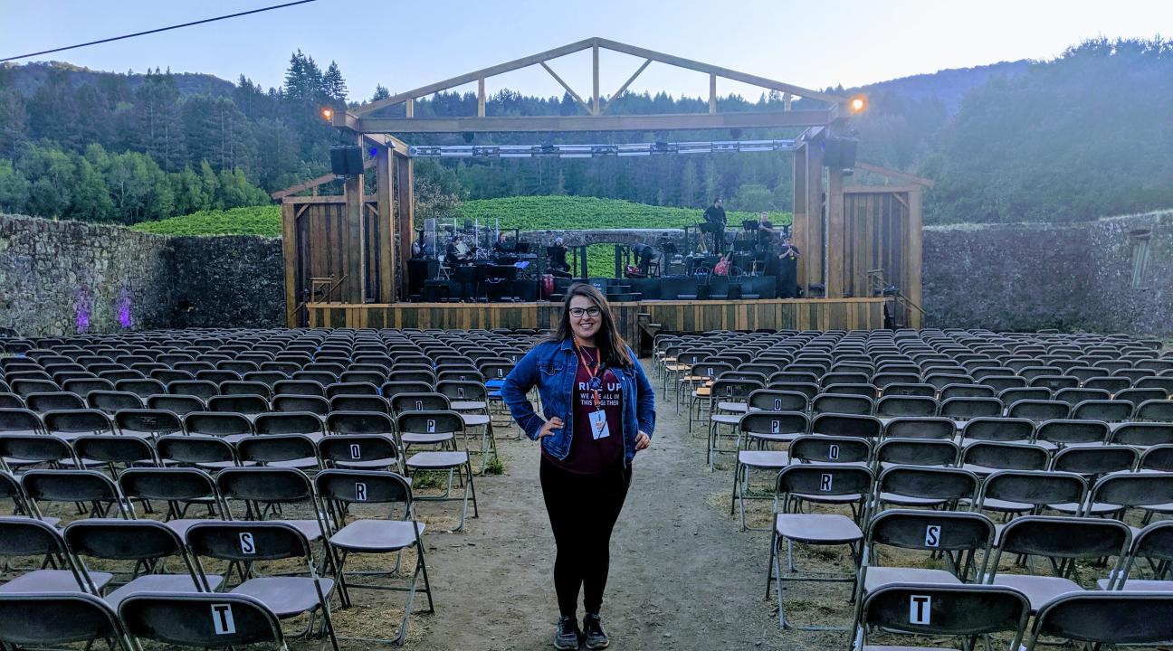 Maggie Simental standing among empty seats in an outdoor theatre