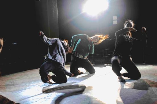 three dancers leading to the side with a bright light above them
