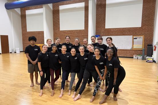 Kristen Daley standing with dancers in black tshirts standing in a rehearsal room