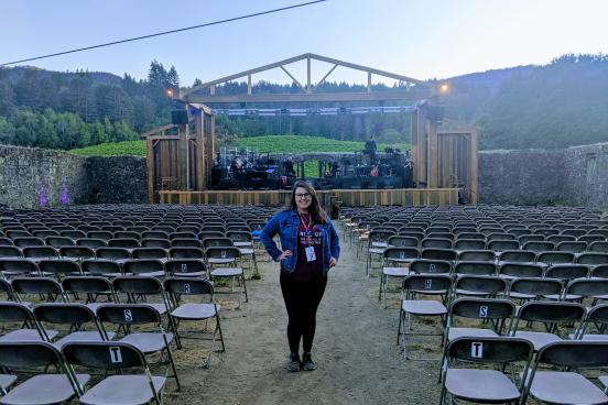 Maggie Simental standing among empty seats in an outdoor theatre