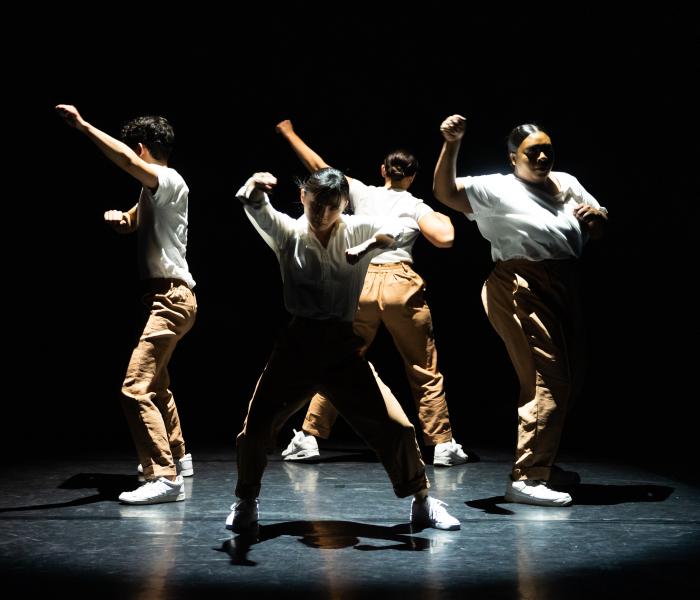 Dancers in a circle with white shirts and khaki pants
