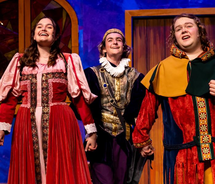 Students in costume holding hands and singing