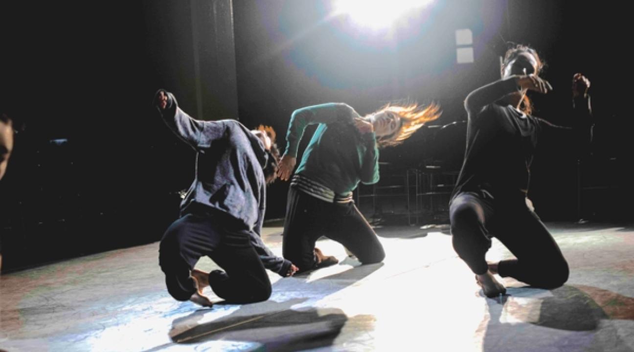 three dancers leading to the side with a bright light above them