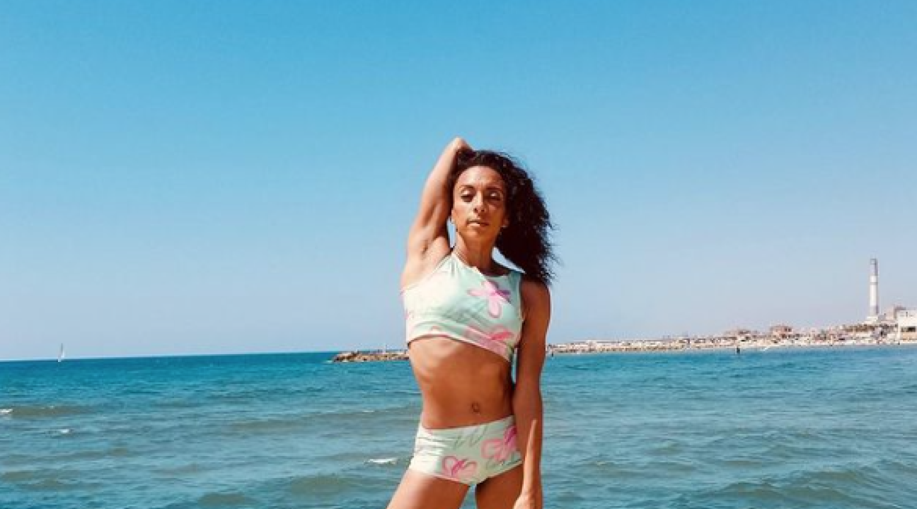 Olivia Bowman-Jackson standing on some rocks by the sea in workout clothes