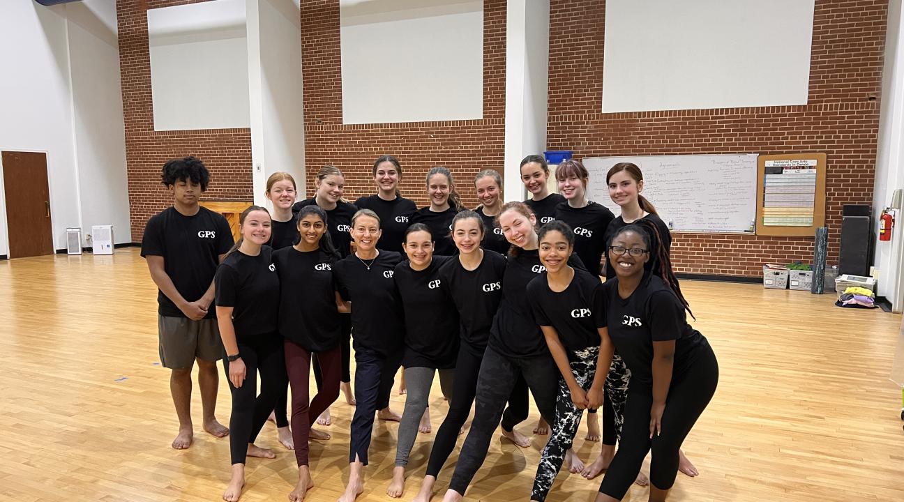 Kristen Daley standing with dancers in black tshirts standing in a rehearsal room