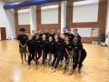 Kristen Daley standing with dancers in black tshirts standing in a rehearsal room