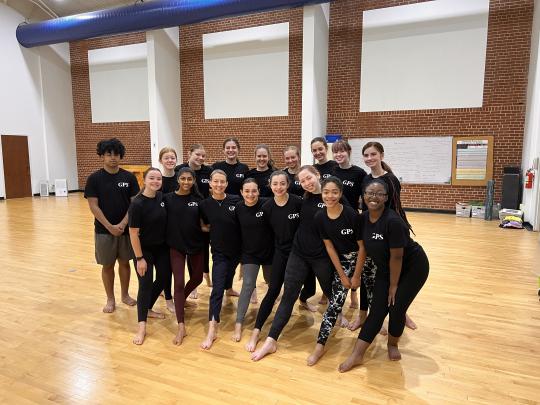 Kristen Daley standing with dancers in black tshirts standing in a rehearsal room