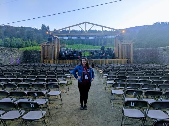 Maggie Simental standing among empty seats in an outdoor theatre