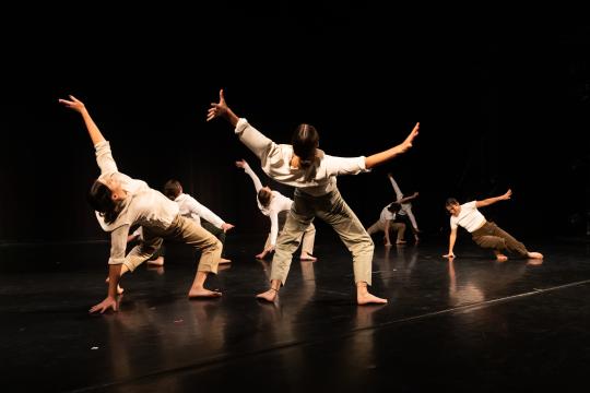 Dancers leaning backward on stage in exaggerated positions